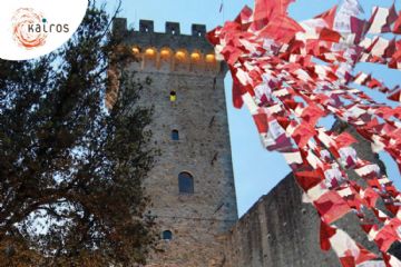 L’immagine mostra la Torre del Castello dei Vescovi di Castelnuovo Magra, fotografata al crepuscolo. Le luci calde illuminano le mura di pietra del castello, creando un’atmosfera accogliente e suggestiva. In alto a destra, si vedono numerosi teli rossi e bianchi mossi dal vento, che si collegano simbolicamente al titolo dell’evento. In alto a sinistra compare il logo di Kairós, caratterizzato da un cerchio arancione con linee dinamiche e il nome scritto in minuscolo. Al centro, nella parte inferiore della locandina, si trova il testo informativo principale: "Siete tutti invitati a creare dei teli rossi e bianchi di 20x50 cm per l’Opera Condivisa Vento di Pace che inaugurerà Il 18 ottobre 2025 a Castelnuovo Magra nella Torre del Castello dei Vescovi".
La frase “Vento di Pace” è evidenziata in rosso vivo e grassetto, diventando il fulcro visivo del messaggio.
Nella parte inferiore sono presenti i loghi degli enti promotori:
•	A sinistra: Rete Spezzina Pace e Disarmo, con un simbolo multicolore a forma di colomba stilizzata.
•	A destra: Comune di Castelnuovo Magra, con lo stemma comunale.
