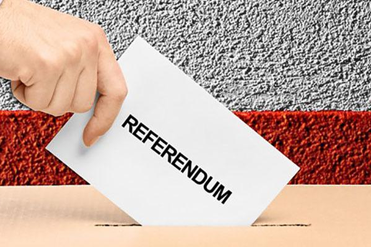 Mano che inserisce scheda referendum nell'urna su sfondo grigio e rosso