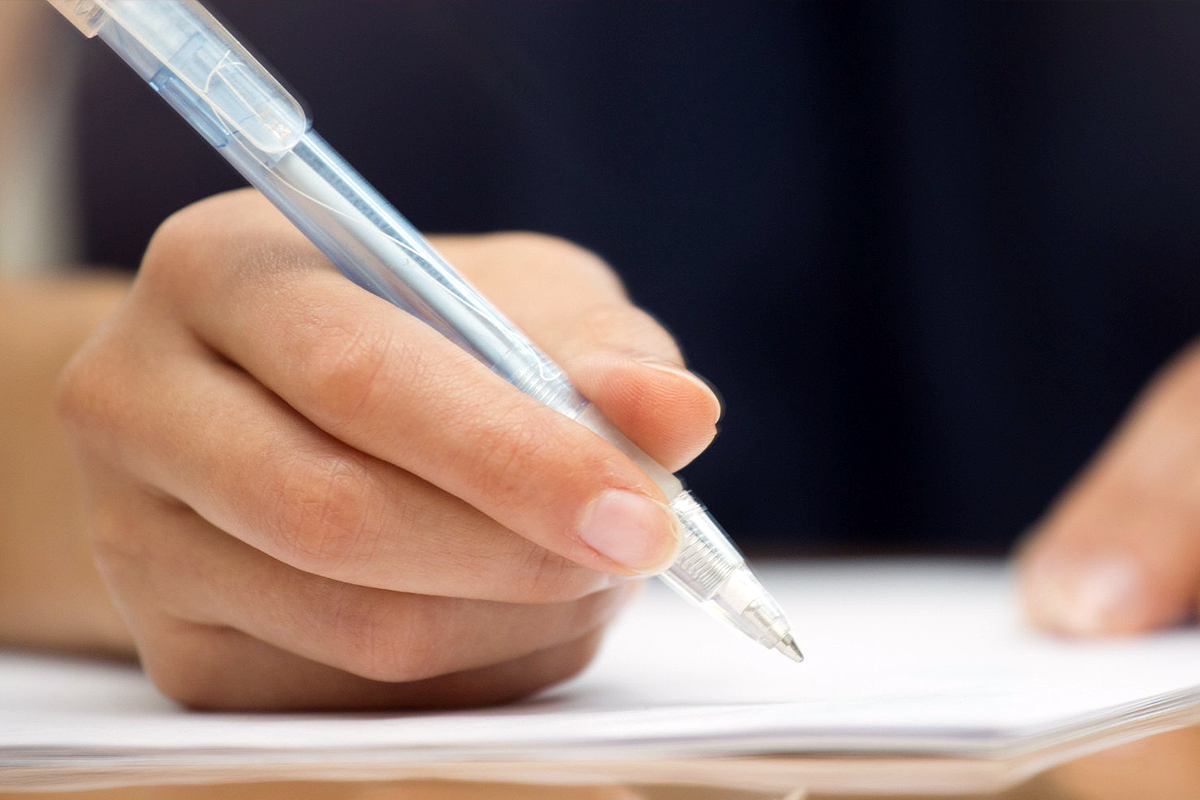 mano con penna che firma su foglio bianco 