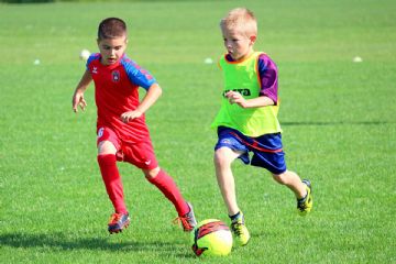 due bambini con completini sportivi che giocano a calcio 
